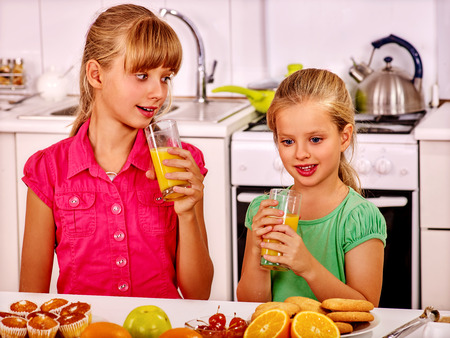 Happy children   breakfast at kitchen. Kids drinking orange fresh.の写真素材