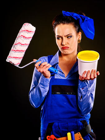 Tired woman builder holding yellow paint cans.の写真素材