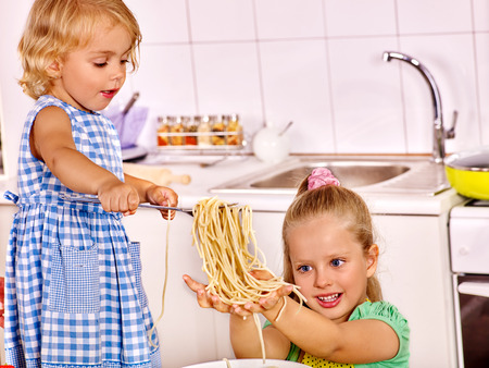 Children  eating spaghetti at kitchen.の写真素材
