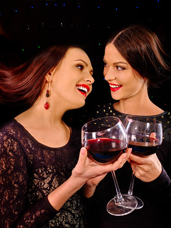 Two sexy lesbian women holdinh red wine glass .Black background.の写真素材