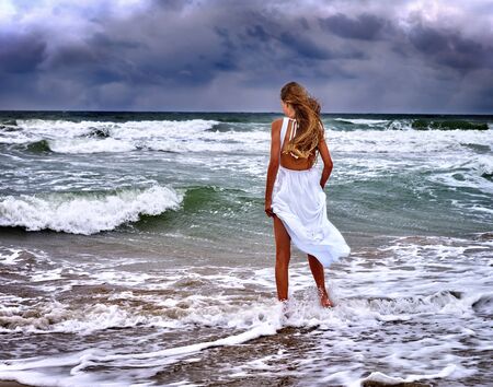 Summer girl sea.  Woman goes at water on coast.の写真素材