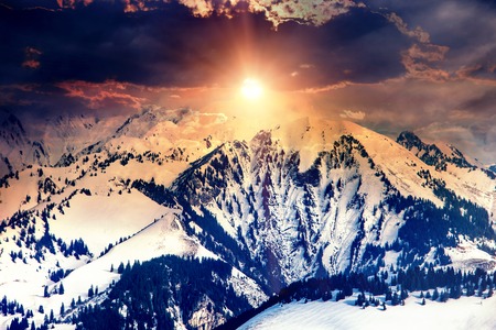 Sun in winter mountains on cloud sky background.の写真素材