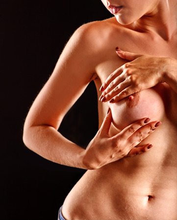 Portrait of  girl touching her beautiful nude breasts and lips on black background.の写真素材