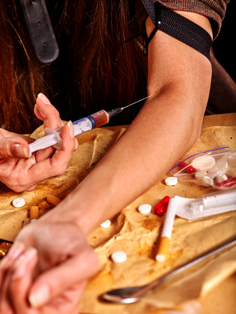 Female drug addict with  tourniquet does intravenously intravenous injection on his arm and  syringe.の写真素材