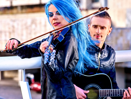 Music street performers  with  extravagant hairstyle girl violinist and man guitarist on blue sky outdoor.の写真素材