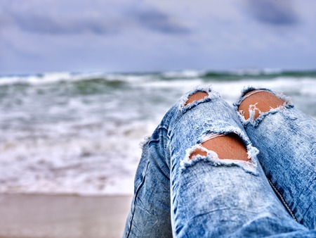 Summer girl sea.  Woman sitting on coast near ocean with waves. Hot dog leg selfie.の写真素材
