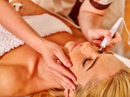 Close up of  blonde nice woman receiving electric facial eyes massage on microdermabrasion equipment...