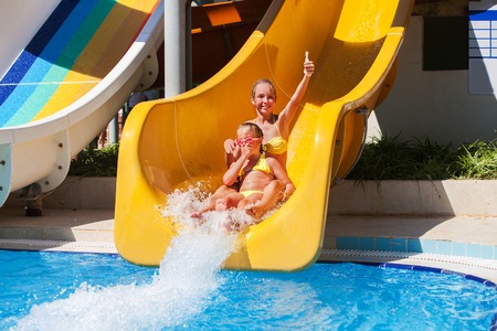 Two girls sisters on water slide at aquapark.