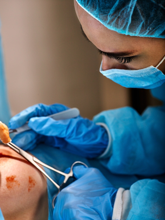 Surgeon wearing gloves operates women's breasts . Doctors face.の写真素材