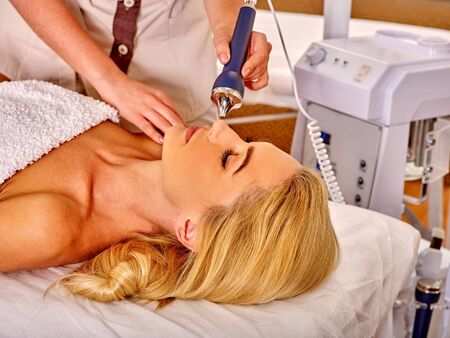 Head of young woman receiving electric ultrusound facial massage at beauty salon. Modern...