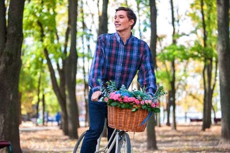 Happy handsome young man looking up ride on bike in park outdoor.の写真素材