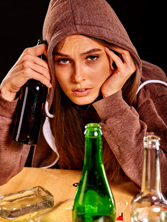 Drunk girl holding green glass bottle of alcohol. Soccial issue alcoholism.の写真素材