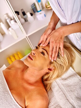Woman middle-aged take face and neck rejuvenating massage in spa salon.の写真素材