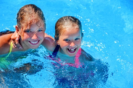 Two different ages children hugging and looking up swim in swimming pool. Summer swimming holiday. Outdoor swimming pool. Children activities lifestyle.の写真素材