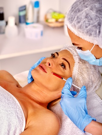 Woman middle-aged in spa salon with beautician. Beauty woman giving botox injection. Injection in nasolabial folds.の写真素材