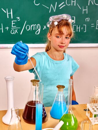 Chemistry child in blue rubber glove holding flask in chemistry class.の写真素材