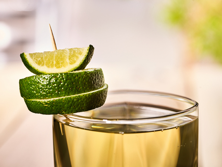 Alcohol drink. On wooden boards is glass with alcohol green transparent drink. A drink number four cocktail green tea is decorated with lime. Country life. Light background.の写真素材