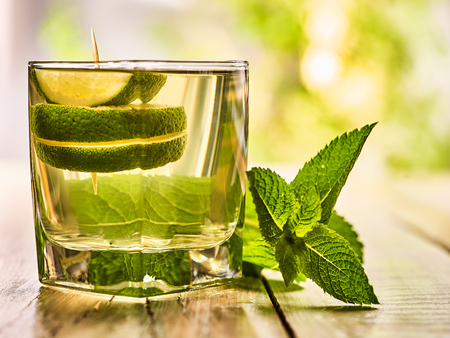 Alcohol drink. On wooden boards is glass with alcohol green transparent drink. A drink number nine cocktail mohito with slice lime. Country life. Outdoor. Light background.の写真素材