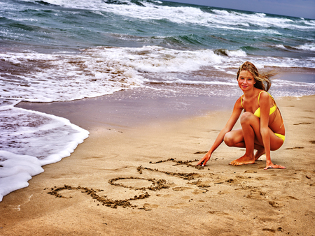 Summer girl sea. Woman in swimsuit written in sand 2017 two thousand and seventeenth year near ocean with waves.の写真素材