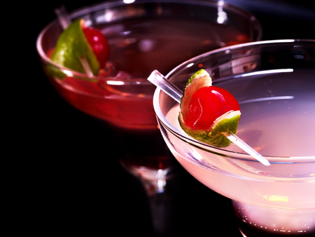 Part of alcohol cocktail in glass .Two pomegranate cocktail glasses with cherry on black background. Cocktail card.の写真素材