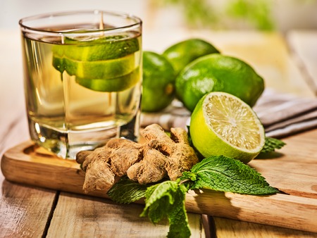 Healthy detox drink with ginger . On wooden boards glass with green tea and mint. A mint ginger drink number twenty four with half lime and napkin. Country life. Light background.の写真素材
