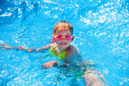 Portrait of child wearing goggles girl on water in swimming pool . Children's healthy lifestyle into blue water. Summer holiday. Outdoor.の写真素材