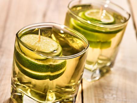 Alcohol drink. On wooden boards are two glasses with alcohol green transparent drink. A drink number sixteen cocktail green tea with lime. Country life. Light background.の写真素材