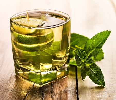 Alcohol drink. On wooden boards is glass with alcohol green transparent drink. A drink number eight mohito cocktail with lime. Country life. Light background.の写真素材