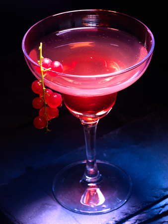 Alcohol cocktail on black background. Pomegranate cocktail decoration red currant branch. Cocktail cardの写真素材