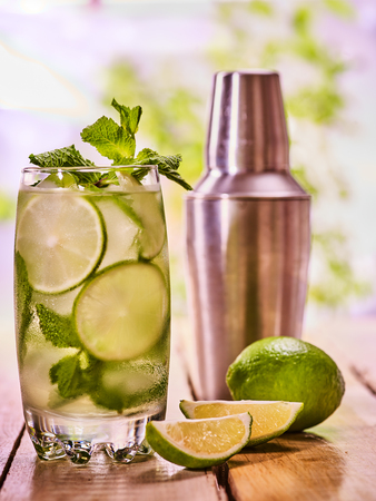 Alcohol drink. On wooden boards three glasses with alcohol drink and ice cubes. A drink number forty eight cocktail mohito with cocktail shaker and mint leaf. Country life. Light background.の写真素材