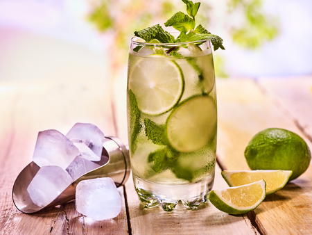 Alcohol drink. On wooden boards is glass with alcohol drink and ice cubes. A drink number thirty four cocktail mohito and scoop ice . Country life cocktail . Outdoor. Light background.の写真素材