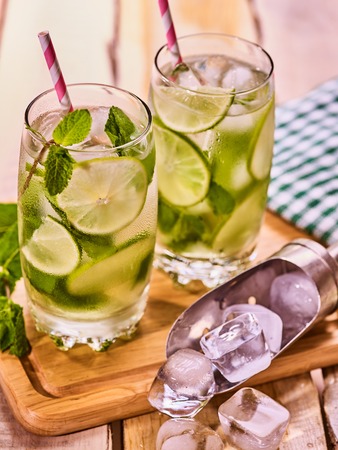 Alcohol drink. On wooden boards three glasses with alcohol drink and ice cubes. A drink number forty three cocktail mohito and scoop ice with straw. Country life. Outdoor. Light background.の写真素材