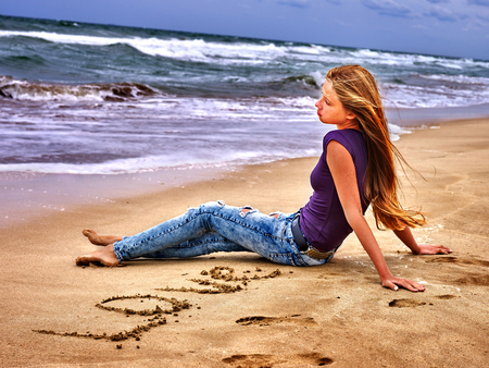 Summer girl sea. Girl draw love word on sand on sea beach.の写真素材
