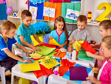 Group kids are making something out of colored paper in primary school.の写真素材