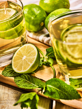 Alcohol drink. On wooden boards three glasses with alcohol drink and ice cubes. A drink number seventy two part of cocktail mohito with lime and mint leaf. Country life. Outdoor. Light background.の写真素材