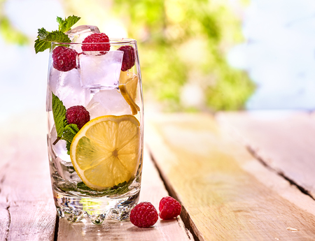 On wooden boards is glass with berries lemon and ice cubes. Cocktail drink number seventy nine with lemon.の写真素材