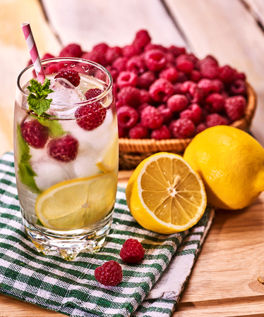 On wooden boards is cocktail glass with berries lemon and ice cubes. Alcohol country cocktail number eighty three with berry basket mint and ice cubes.の写真素材