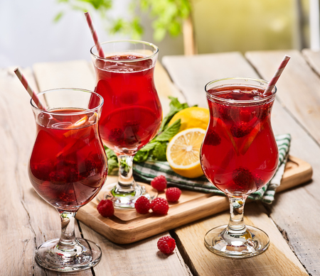 On wooden boards is ice cold beverage glass with red raspberry lemon cocktail . Alcohol country cocktail beverage number ninety eight with mint. Cocktail on outdoor.の写真素材