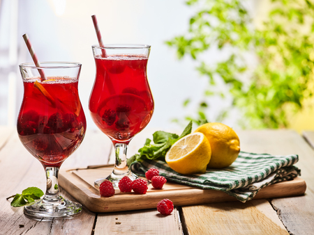On wooden boards are ice cold cocktail two glasses with red berries lemon cocktail . Alcohol country cocktail beverage number hundred thirty one with leaf mint. Outdoor cocktail beverage .の写真素材