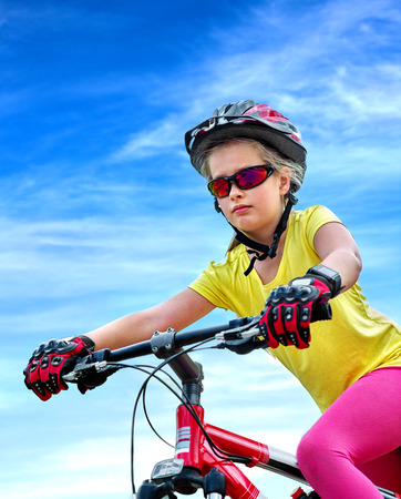Bikes cycling child. Girl rides bicycle. Little girl in cycling. Cycling is good for child health. Cyclist look away aganist blue sky.の写真素材