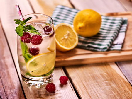 Alcohol cocktail. On wooden boards glass with raspberry alcohol cocktail and ice cubes. Drink number hundred nineteen cocktail raspberry mojito with lime and mint leaf. Country life. Light background.の写真素材