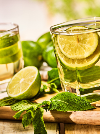 Country drink. On wooden boards are two glasses with green transparent drink . A drink number hundred five mojito with mint leaf on sunlight . Country life. Light background.の写真素材