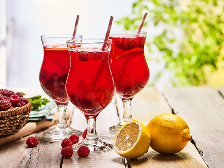 Wooden boards are ice cold beverage glasses with red raspberry lemon cocktail . Alcohol country cocktail beverage number hundred thirty six with raspberry basket. Cocktail beverage corporate outdoor.の写真素材