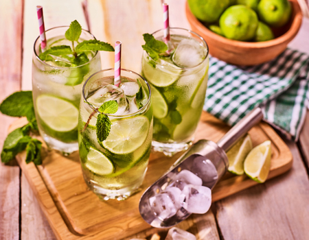 Alcohol drink. On wooden boards three glasses with straw alcohol drink and ice cubes. A drink number hundred thirteen cocktail mohito and scoop with glue bowl. Country life. Outdoor. Light background.の写真素材
