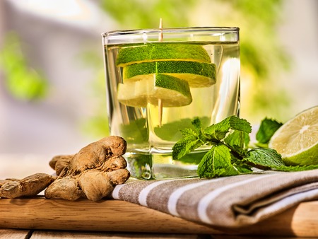 Healthy detox drink with ginger . On wooden boards glass with lime green tea and mint. Mint ginger drink number hundred six with half and slice lime and striped napkin. Country life. Light background.の写真素材