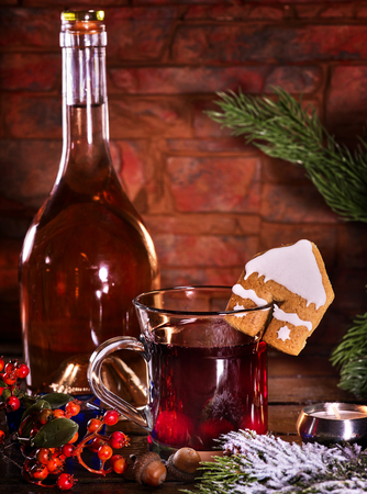 Still life of winter hot drink with bottle of red wine . Warming mulled wine with cookie in form of house on brick wall.の写真素材