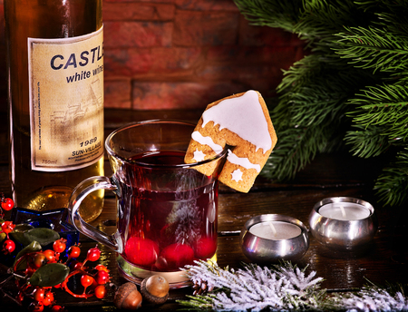Still life of warming drink with bottle of red wine . Label on bottle of wine. Warming mulled wine with cookie in form of house on brick wall.の写真素材