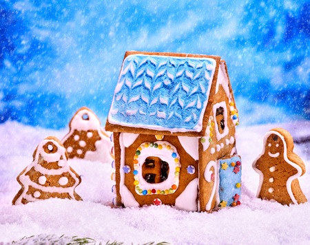 Gingerbread man , house near tree Christmas cookie with blue sky and falling winter snow. Xmas food decoration.の写真素材