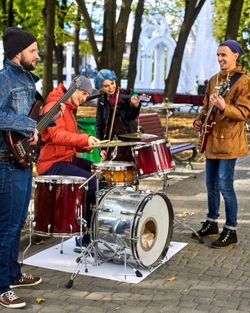 Festival music band. Friends playing on percussion instruments in city park. Fountain and trees in the background.の写真素材