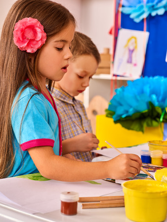 Small students painting in art school class. Child drawing by paints on table. Girl and boy together. Portrait of little girl in kindergarten. Drawing education develops creative abilities of children.の写真素材